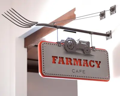 a sign for a farmancy cafe hanging from a wire at Padre Hotel in Bakersfield