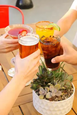 a group of people holding up drinks on a table at Padre Hotel in Bakersfield