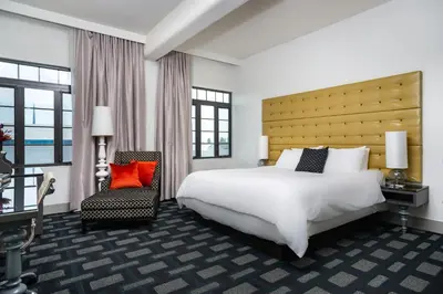 a hotel room with a large bed and a chair at Padre Hotel in Bakersfield