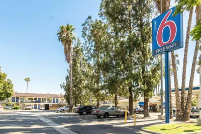 a first aid sign on a street with palm trees at Motel 6 Riverside, CA - UCR East in Riverside