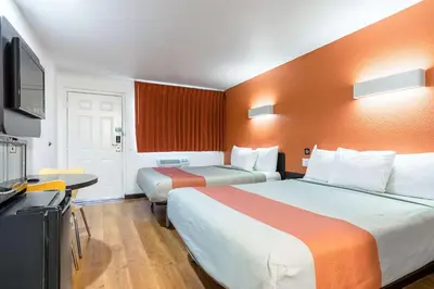 a hotel room with two beds and a flat screen tv at Motel 6 Riverside, CA - UCR East in Riverside