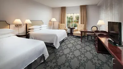 a hotel room with two beds and a flat screen tv at Anaheim Majestic Garden Hotel in Anaheim