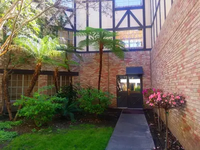 a brick building with a door and a courtyard with flowers at Anaheim Majestic Garden Hotel in Anaheim