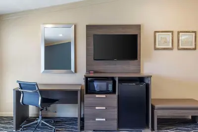 a hotel room with a tv and a desk and a chair at Best Western Plus Hill House in Bakersfield