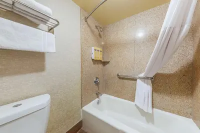 a bathroom with a toilet and a shower curtain at Best Western Plus Hill House in Bakersfield