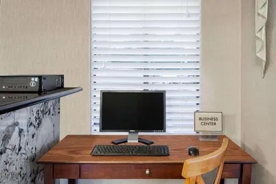 a desk with a computer monitor and a keyboard at Days Inn by Wyndham Anaheim Near the Park in Anaheim