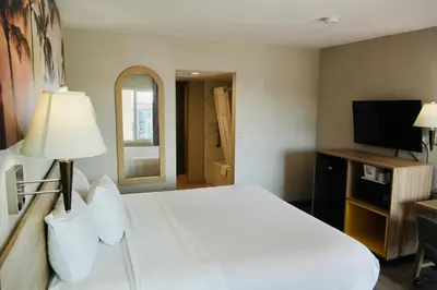 a bedroom with a white bed and a flat screen tv at Days Inn by Wyndham Anaheim Near the Park in Anaheim