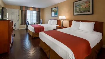 a hotel room with two beds and a television at Best Western Palm Garden Inn in Westminster