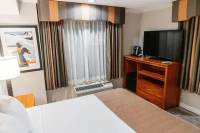 a hotel room with a bed and a flat screen tv at Best Western Palm Garden Inn in Westminster
