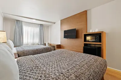 a hotel room with two beds and a flat screen tv at Brookhurst Plaza Inn in Anaheim