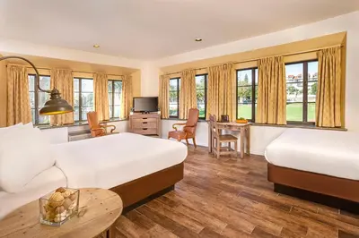 a hotel room with two beds and a desk at Clocktower Inn Ventura in Ventura