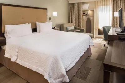 a hotel room with a large white bed and a chair at Hampton Inn Los Angeles-West Covina in West Covina