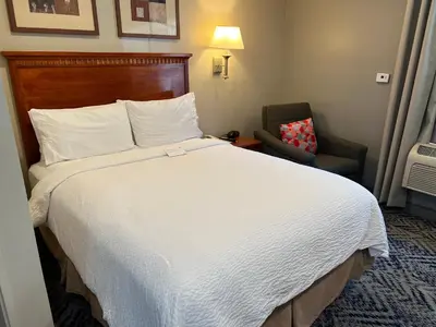 a hotel room with a large bed and a chair at Candlewood Suites LAX Hawthorne by IHG in Hawthorne