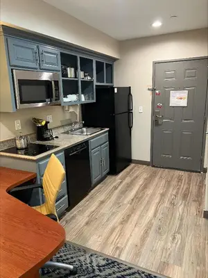 a kitchen with blue cabinets and a black refrigerator at Candlewood Suites LAX Hawthorne by IHG in Hawthorne