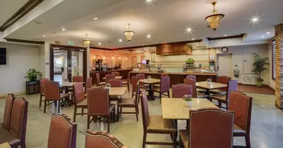 a restaurant with tables and chairs and a kitchen at Ayres Hotel Chino Hills Ontario in Chino Hills