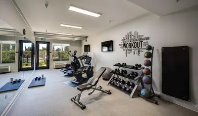 a gym with several tread machines and a flat screen tv at Ayres Hotel Chino Hills Ontario in Chino Hills