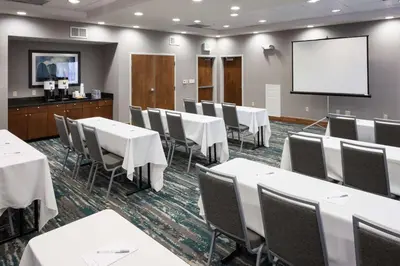 a conference room with white tables and chairs and a screen at Hampton Inn Los Angeles Orange County Cypress in Cypress