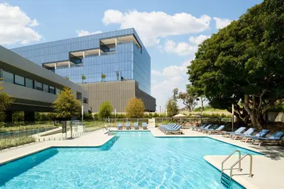 a swimming pool with lounge chairs and a building at Hilton Los Angeles-Culver City, CA in Los Angeles