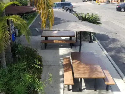 two picnic tables and an umbrella on a sidewalk at Casa Bella Inn Downtown LA in Los Angeles