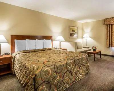 a hotel room with a large bed and a chair at California Inn and Suites Bakersfield in Bakersfield