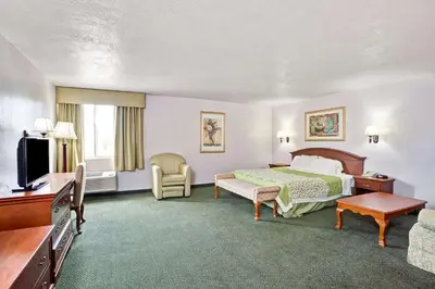 a hotel room with a bed and a television at Days Inn & Suites by Wyndham Fullerton in Fullerton