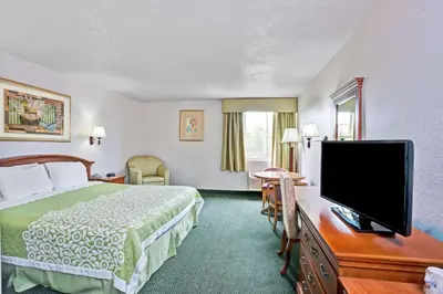 a hotel room with a bed and a flat screen tv at Days Inn & Suites by Wyndham Fullerton in Fullerton