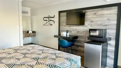 a bedroom with a bed and a tv on a wall at Motel 6 Pico Rivera - Los Angeles, CA in Pico Rivera