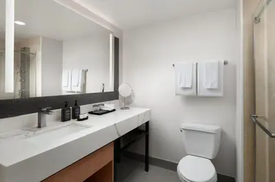 a bathroom with a toilet and a sink and a mirror at Sheraton Ontario Airport Hotel in Ontario