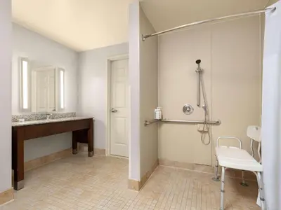 a bathroom with a shower and a sink and a chair at La Quinta by Wyndham Santa Clarita - Valencia in Stevenson Ranch