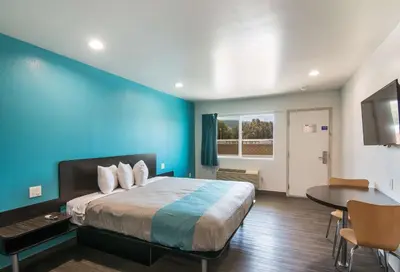 a bedroom with a blue wall and a bed and a table at Motel 6-South El Monte, CA - Los Angeles in South El Monte