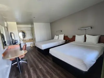 a hotel room with two beds and a desk and a table at Motel 6 Barstow, CA - Lenwood Road in Barstow