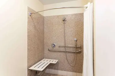 a shower with a bench in a bathroom at Travelodge by Wyndham Brea in Brea
