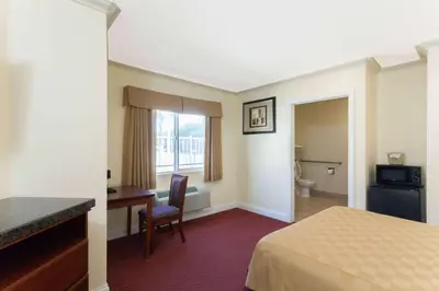 a hotel room with a bed and a desk and a bathroom at Travelodge by Wyndham Brea in Brea