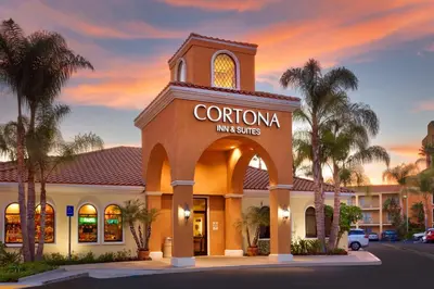 a corona inn and suites building with palm trees at Cortona Inn and Suites Anaheim Resort in Anaheim
