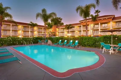 a large swimming pool with chairs and a hotel at Cortona Inn and Suites Anaheim Resort in Anaheim