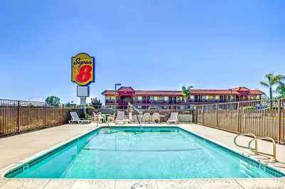 a swimming pool with a hotel in the background at Super 8 by Wyndham Upland Ontario CA in Upland