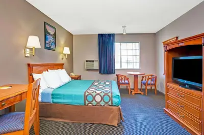 a hotel room with a bed and a desk and a television at Super 8 by Wyndham Upland Ontario CA in Upland