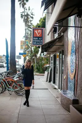 a woman walking down a sidewalk while talking on a cell phone at Inn at Venice Beach in Los Angeles
