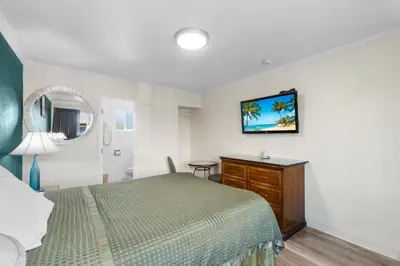 a bedroom with a bed and a dresser and a mirror at Aristocrat Motel in Baldwin Park