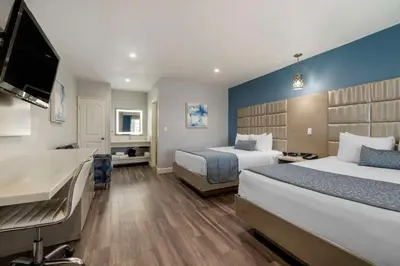 a hotel room with two beds and a flat screen tv at Best Western Orange Plaza in Orange