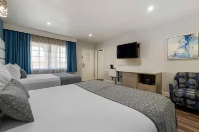 a hotel room with two beds and a flat screen tv at Best Western Orange Plaza in Orange