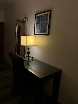 a table with a lamp and a chair in a room at Howard Johnson by Wyndham Bakersfield in Bakersfield