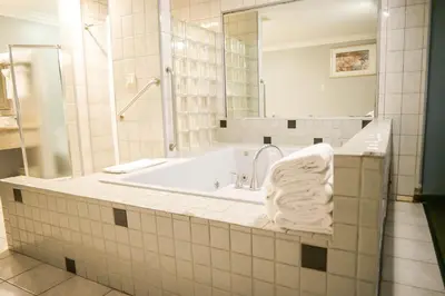 a bathroom with a tub with a mirror and a towel at Days Inn by Wyndham West Covina in West Covina