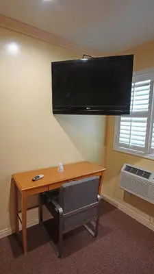 a room with a desk with a television on a wall at Rosa Bell Motel - Los Angeles in Los Angeles