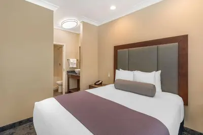 a bedroom with a large bed with a large headboard at Best Western PLUS Avita Suites in Torrance