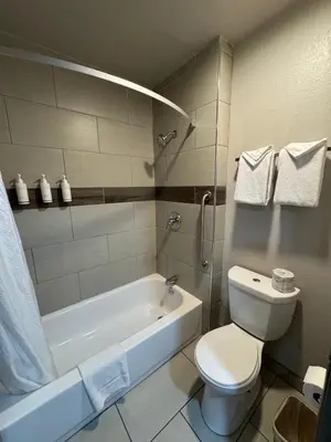 a bathroom with a toilet and a tub and a sink at Days Inn by Wyndham Barstow in Barstow