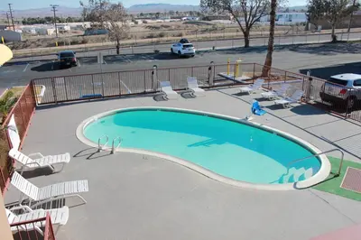 a large swimming pool with chairs and a parking lot at Days Inn by Wyndham Barstow in Barstow
