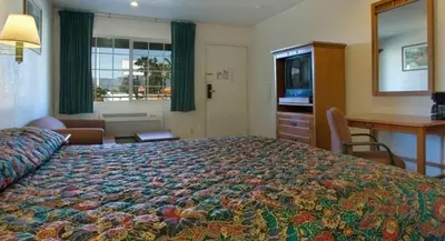 a hotel room with a large bed and a desk at Orange Show Inn in San Bernardino