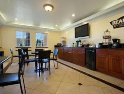 a dining room with a table and a flat screen tv at Orange Show Inn in San Bernardino