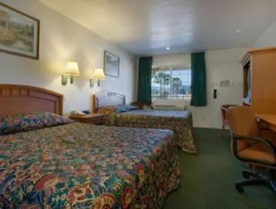 a hotel room with two beds and a desk at Orange Show Inn in San Bernardino